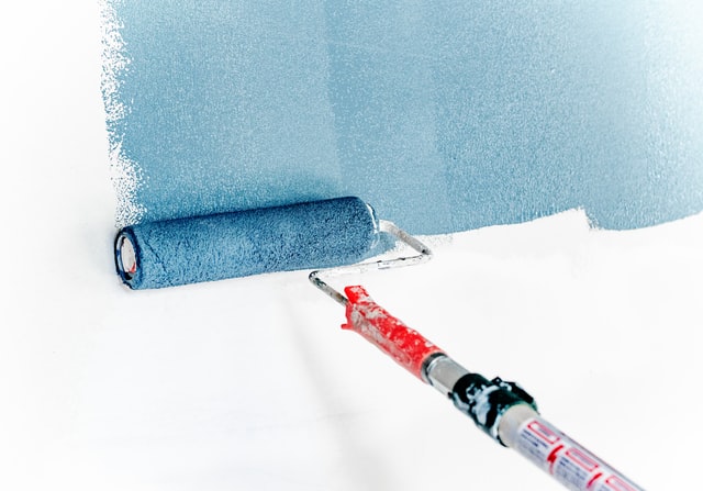 blue paint being applied to white wall on roller